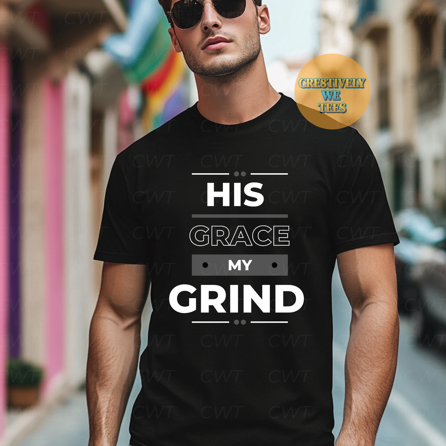 Man wearing a black T-shirt that reads “His Grace My Grind” in bold typography, standing confidently in an urban setting.