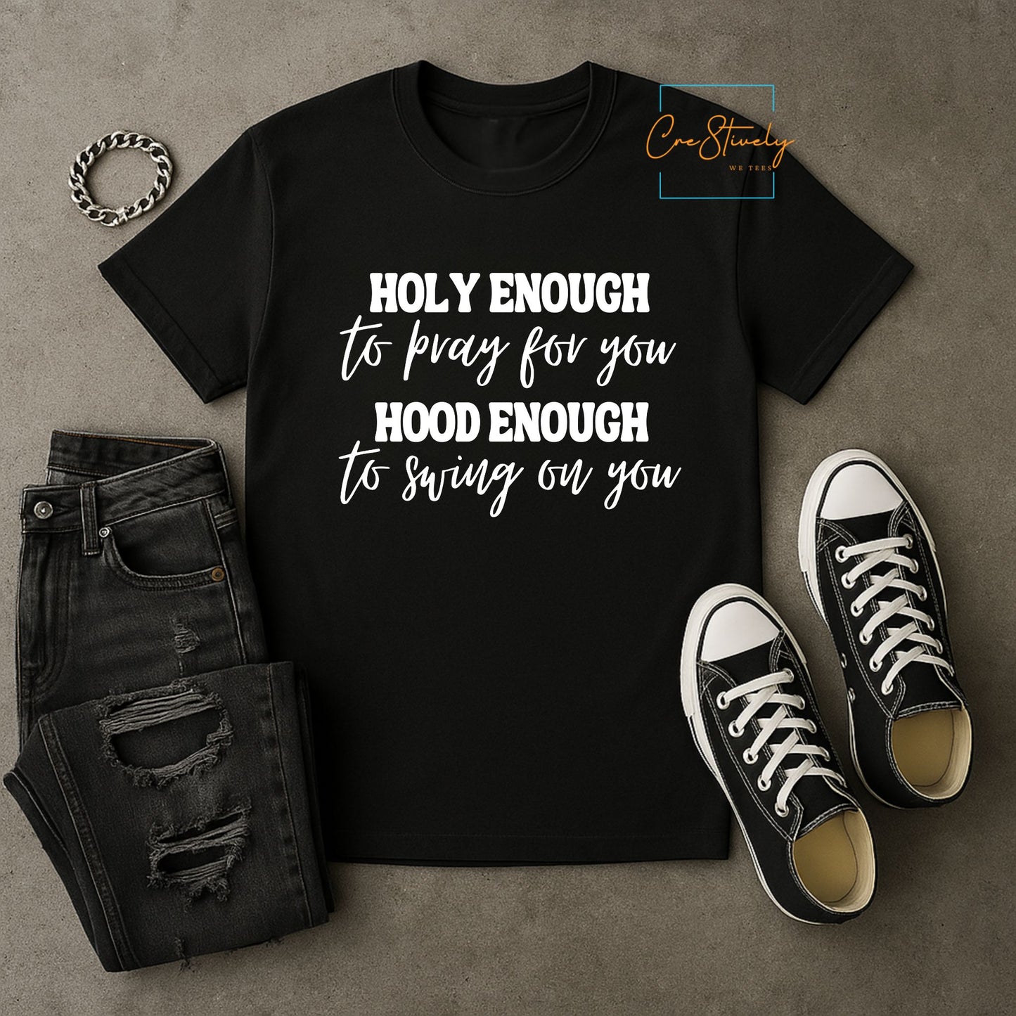 Black “Holy Enough to Pray, Hood Enough to Swing on You” t-shirt styled with black ripped jeans and black Converse sneakers on a neutral background.