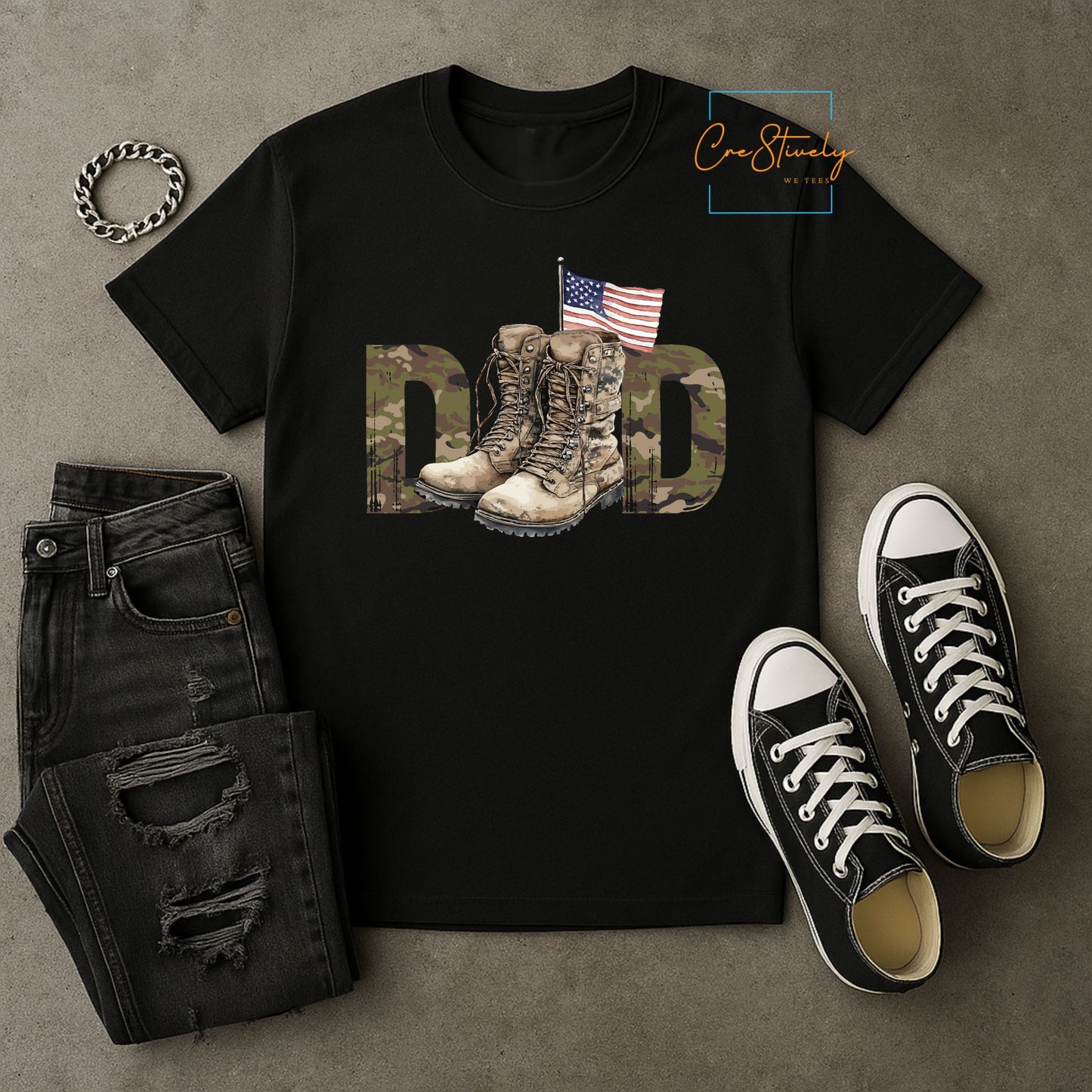 Flat lay of black military dad t-shirt with camo letters, combat boots, and U.S. flag