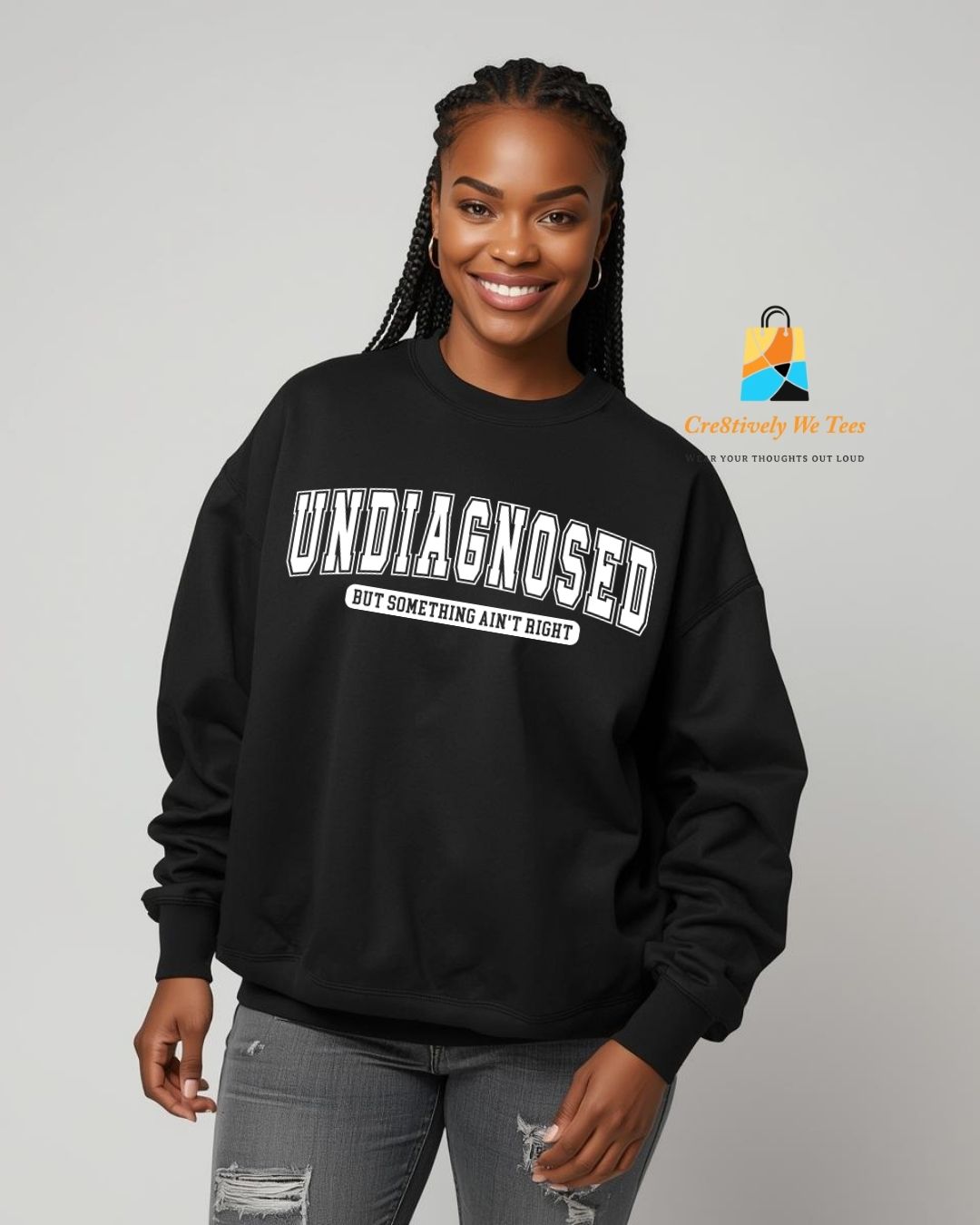 Person wearing a black sweatshirt with text saying "Undiagnosed but something ain't right", standing against a plain background
