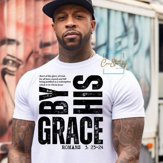 A man wearing a white t-shirt with bold vertical text that reads “By His Grace – Romans 3:23-24,” designed in distressed black font. Faith-based streetwear with a powerful scripture message.