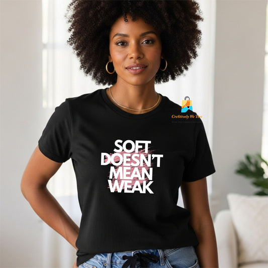 Woman wearing a black statement t-shirt that reads “Soft Doesn’t Mean Weak,” showcasing a confident, relaxed fit for everyday wear.